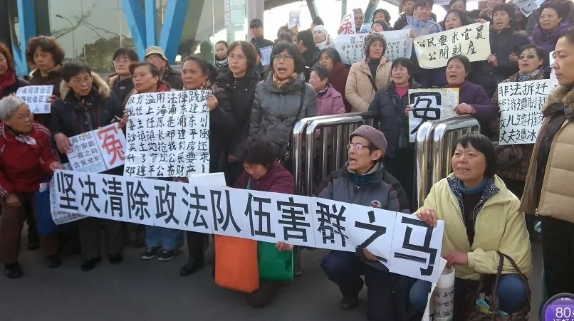 Petitioners hold banners at the Shanghai Expo Center, site of the annual political "Two Sessions." One banner reads, “Clear Away the Black Horse in Political and Legislative Affairs Committee!“ Jan. 19, 2014. (Provided by a petitioner)