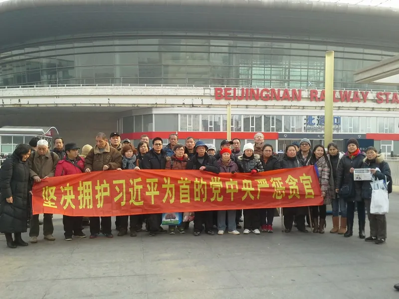 Petitioners who have come to Beijing to seek redress of grievances raise a banner that reads, “We firmly support the Party Central Committee, headed by Xi Jinping, in punishing corrupt officials” in front of the Beijing South Railway Station on Jan. 24, 2014.(Human Rights Campaign in China)
