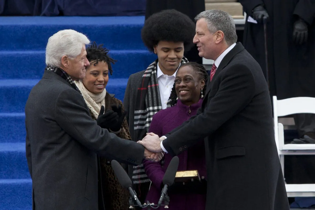 Former President Bill Clinton (L) shakes hands with New York Mayor Bill de Blasio (R) as his daughter, Chiara, son, Dante, and wife, Chirlane McCray, look on, at the inauguration ceremony at New York City Hall on Jan. 1, 2014. (Samira Bouaou/Epoch Times)