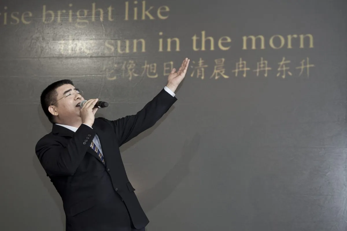 Chen Guangbiao sings karaoke at a press conference he called for the morning of Jan. 7, 2014, in a hotel in New York City. Lyrics to the song he is singing, in Chinese and English, were projected onto the wall behind him. (Samira Bouaou/Epoch Times)
