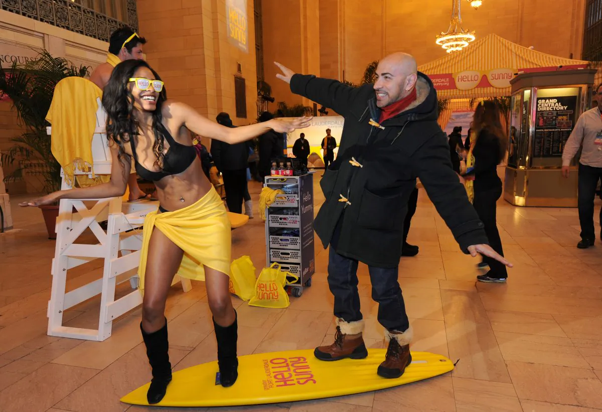 Sisco Muniz surfs with a model at the Hello Sunny Beach promotion at Grand Central Terminal in New York, Jan. 28, 2014. (Diane Bondareff/Invision for Greater Fort Lauderdale/AP)