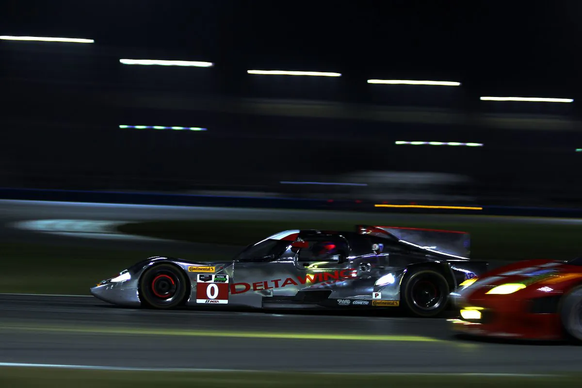 The DeltaWing DWC13 sweeps past one of the many GTD Ferraris on the sort straight connecting Daytona International Speedway’s East and West Horseshoes during TUSCC Roar Before the 24 night practice, Jan. 4, 2014. (Chris Jasurek/Epoch Times) 
