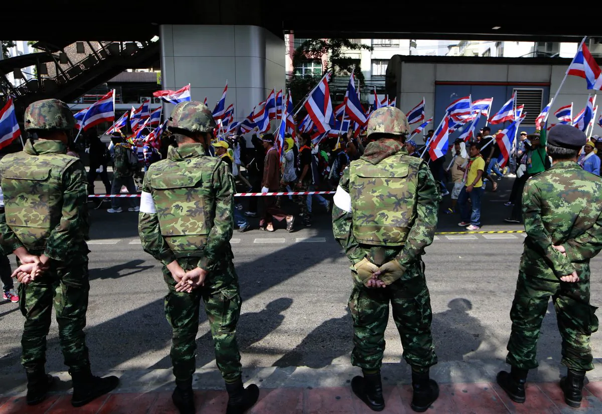 Thai soldiers watch anti-government protesters march on the street past them during a rally Wednesday, Jan. 22, 2014 in Bangkok, Thailand. (AP Photo/Wason Wanichakorn)