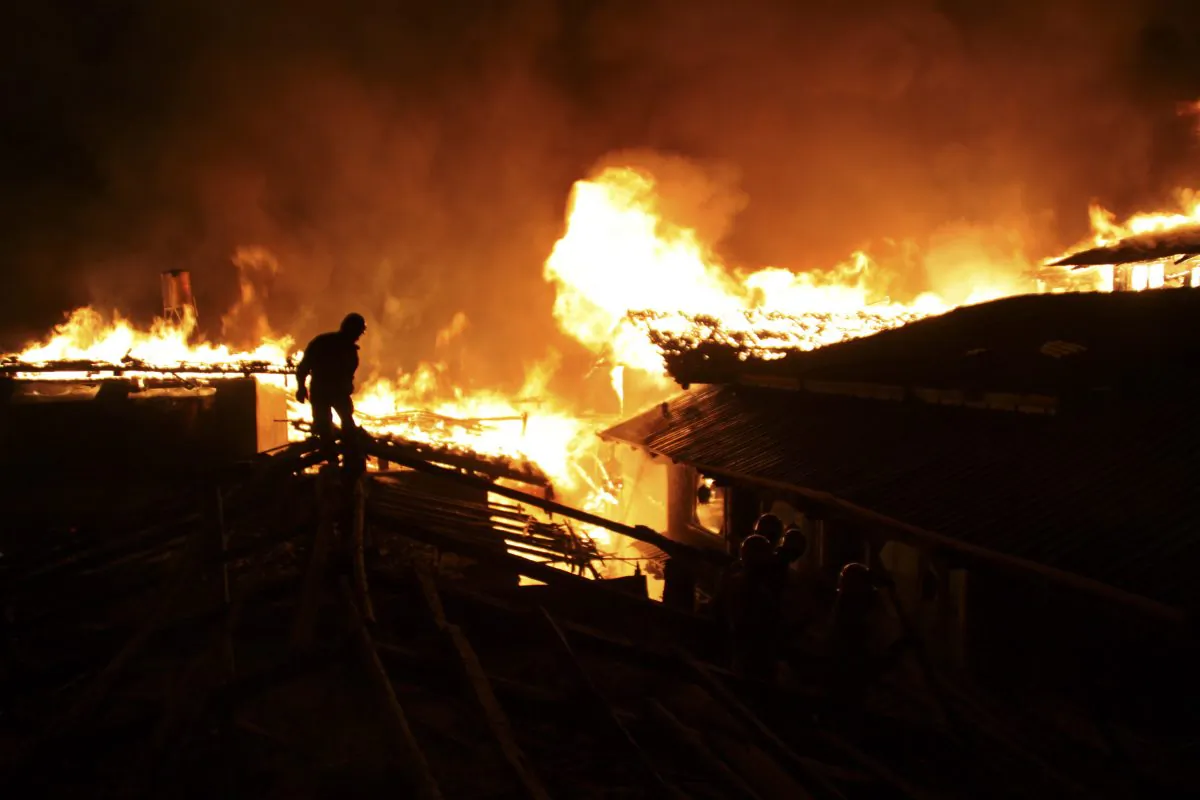 A firefighter works on a roof of a wooden building while a fire ravages ancient Dukezong town in Shangri-la county, in southwestern China's Yunnan province, Saturday Jan. 11, 2014. The 10-hour inferno has razed the ancient Tibetan town in the province that's popular with tourists. (AP Photo) CHINA OUT