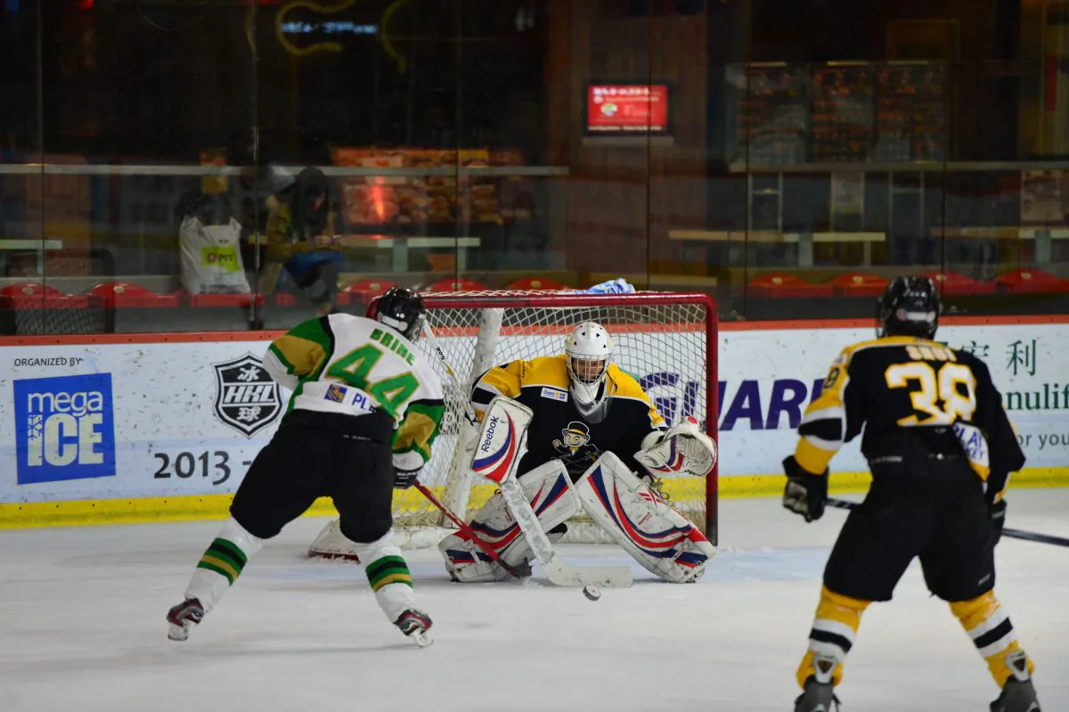 Macau Aces Andy Brine nails the overtime winner between the legs of Hong Kong Tycoon’s goalie Emerson Keung in their CIHL match at Mega Ice on Saturday Jan 25, 2014. (Bill Cox/Epoch Times)