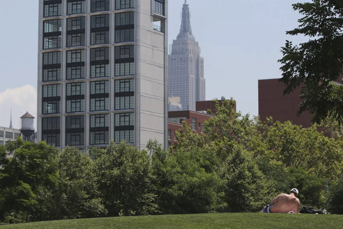 With the Empire State Building and a residential building in the background, a man sunbathes in Hudson River Park, Manhattan, New York, July 16, 2013. (Mary Altaffer/AP)