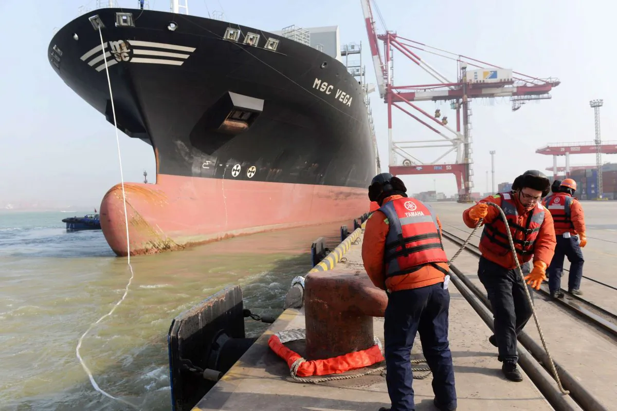 Workers prepare for a container ship to berth at the port of Qingdao, in northeast China's Liaoning province on January 20, 2014.