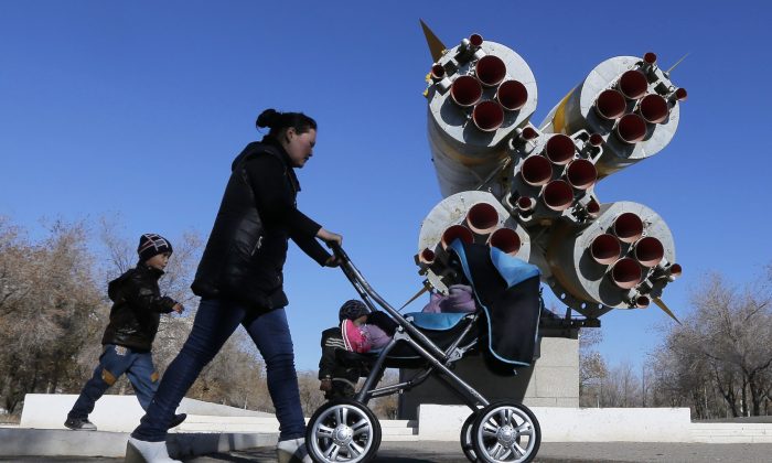A woman walks with her children past a monument of a Soyuz rocket at the Baikonur cosmodrome in Kazakhstan on Nov. 3, 2013. Two Canadian cameras installed by Russian astronauts at the international space station last week have been removed for safety reasons. (AP Photo/Dmitry Lovetsky)