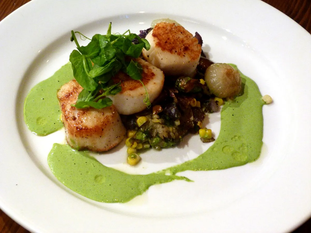 Grilled scallops, blue potatoes, stewed mushrooms, roasted corn, in an arugula reduction. (Courtesy of Manos Angelakis)