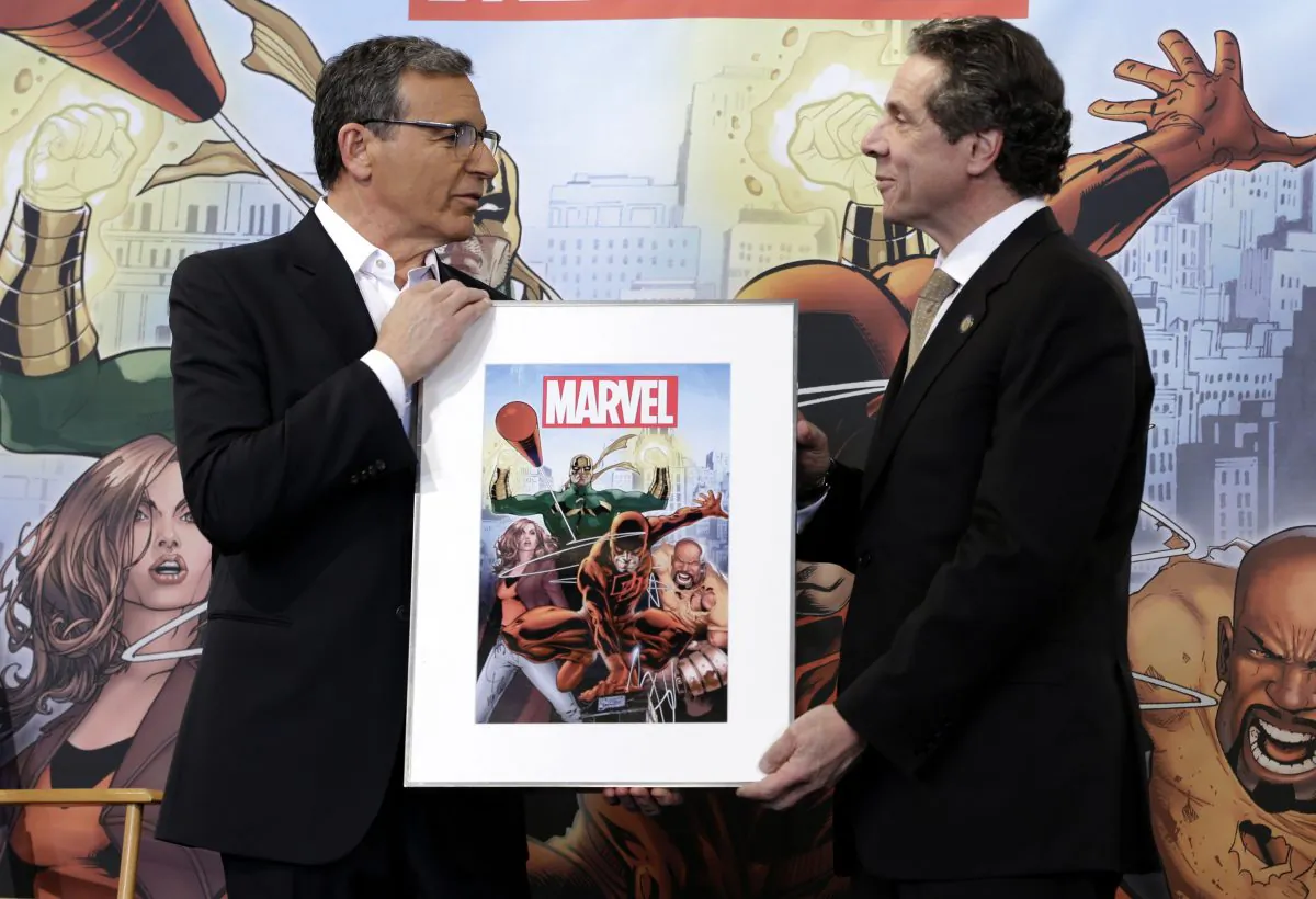 Disney CEO Bob Iger, left, presents New York Governor Andrew Cuomo with a signed poster during a news conference in New York, Wednesday, Feb. 26, 2014. Cuomo and Iger helped to announce the scheduled filming of a TV series based on Marvel characters in New York State. (AP Photo/Seth Wenig)