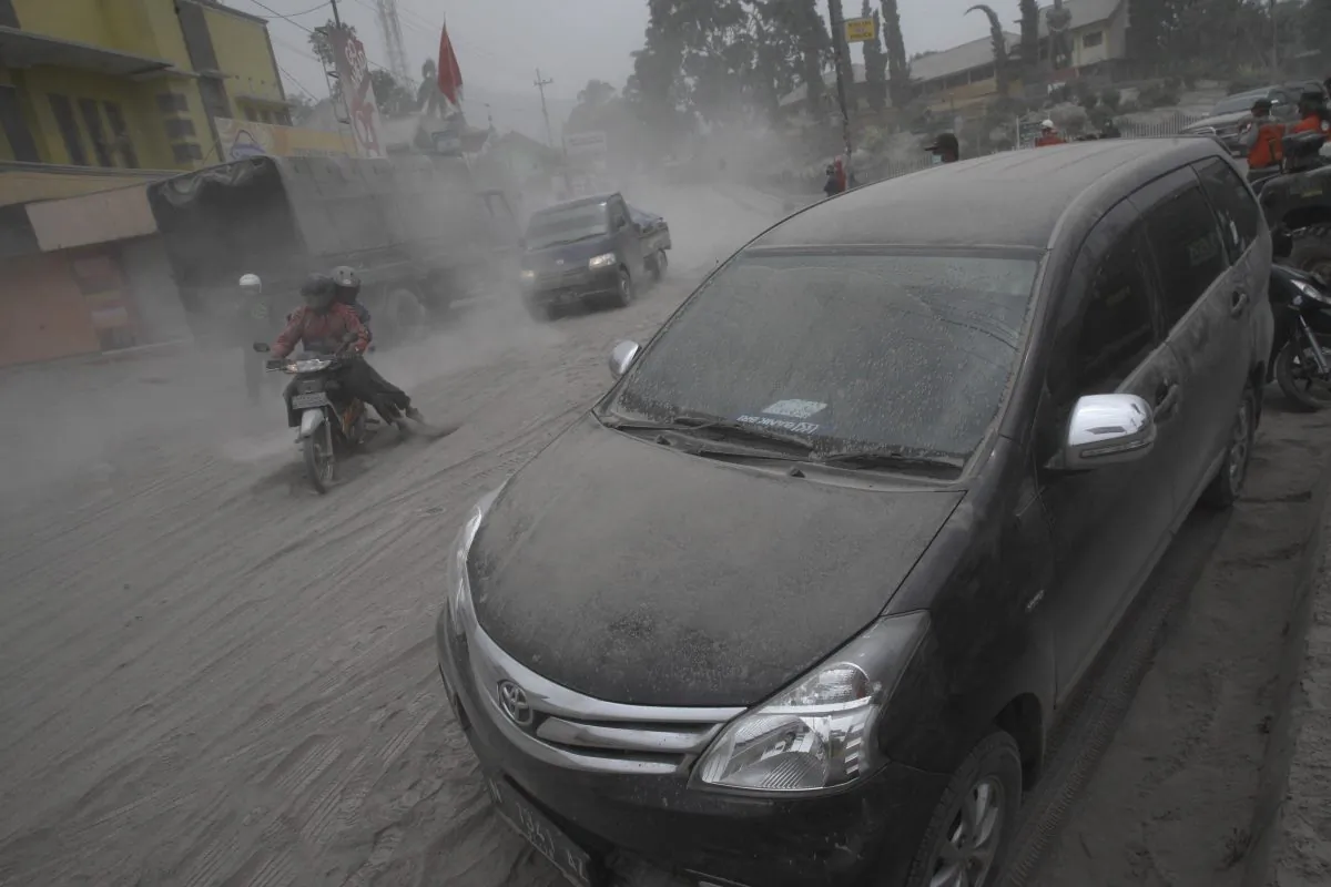 Vehicles and a street are covered with volcanic ash from an eruption of Mount Kelud in Malang, East Java, Indonesia, Saturday, Feb. 15, 2014. (AP Photo/Trisnadi)