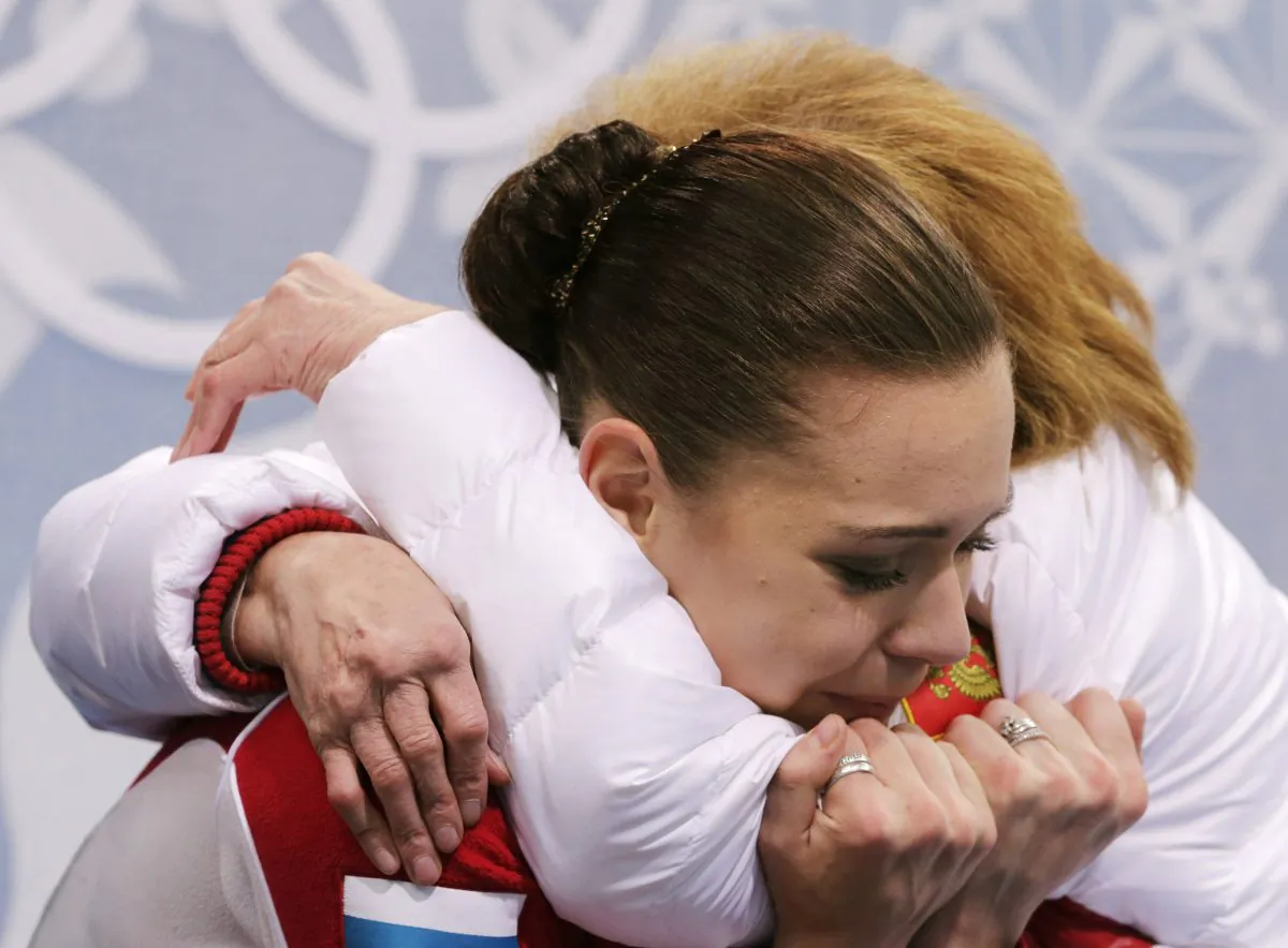 Adelina Sotnikova of Russia embraces her coach Elena Buianova in the results area after completing her routine in the women's free skate figure skating finals at the Iceberg Skating Palace during the 2014 Winter Olympics, Feb. 20, 2014, in Sochi, Russia. (AP Photo/Bernat Armangue)