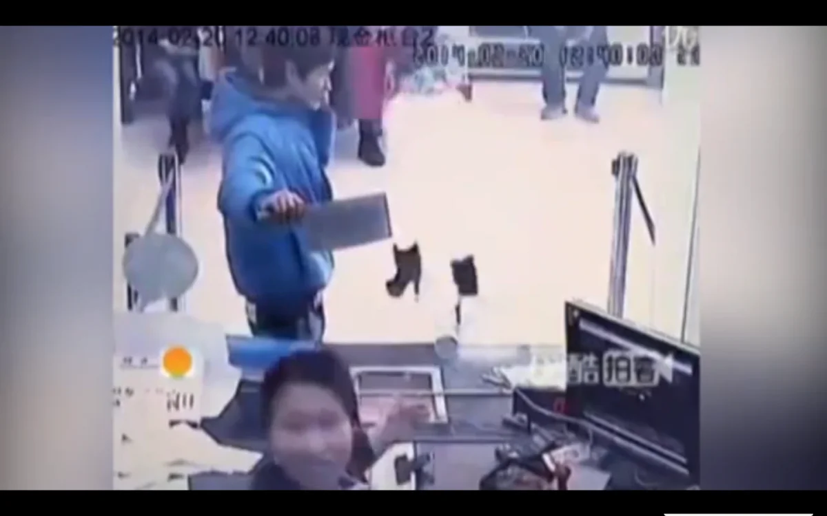 Screenshot of security footage showing a man with a cleaver trying to rob a bank in Shanghai, while talking on his cellphone. (Screenshot/YouTube)