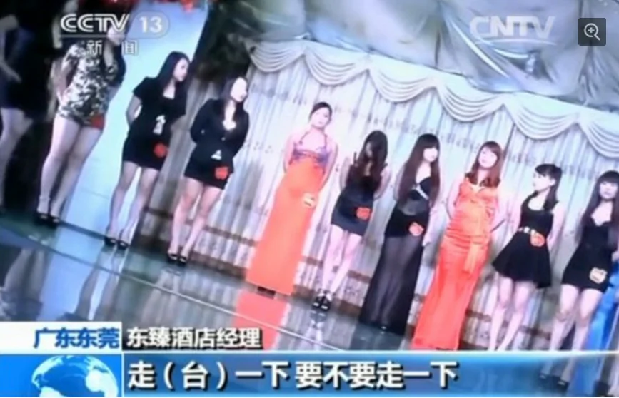 A group of girls stand on a stage with price tags attached, at a hotel in Dongguan, Guangdong Province, January 2014. The authorities recently cracked down on the sex industry in the city. (Screenshot/CCTV)