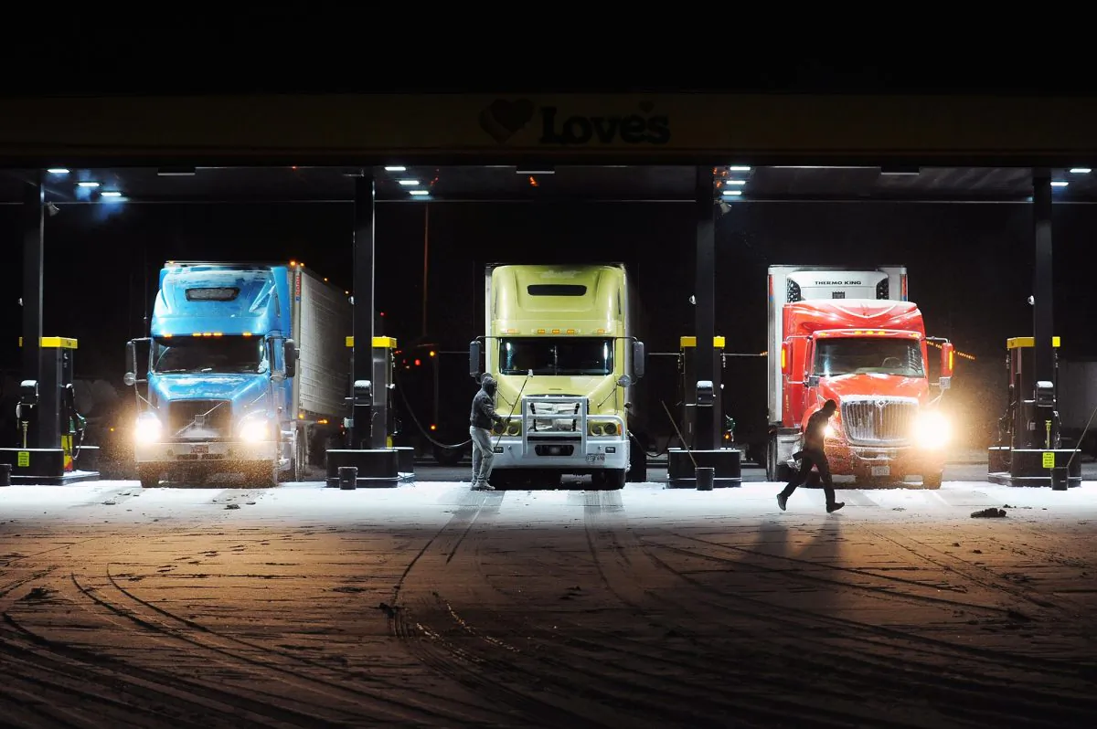 Semi truck drivers fill up with gas as at a Love's Travel Stop in Napavine, Wash. on Thursday, Feb. 6, 2014. Much of Southwest Washington was blanketed in several inches of snow of Thursday causing dozens wrecks along Interstate 5. Bad weather and heavy traffic forced a number of the drivers to break for the night at the Napavine truck stop. (AP Photo/The Chronicle, Pete aster)