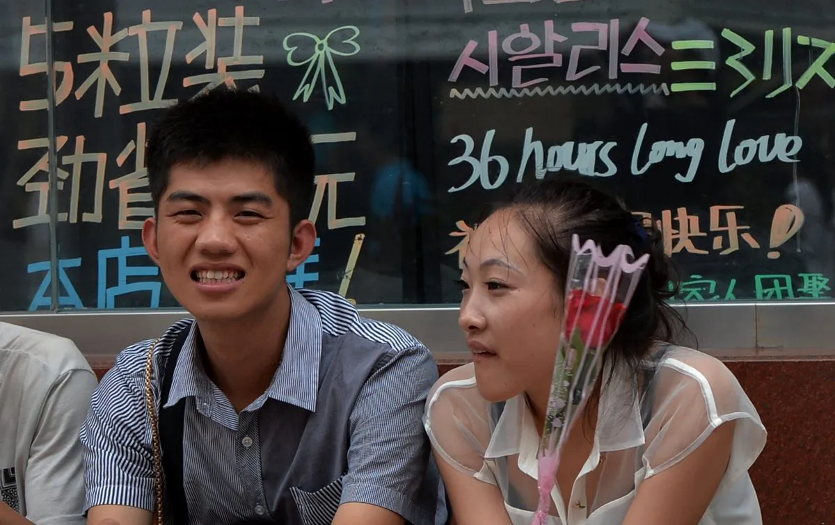 A young girl holds a rose next to her boyfriend in Beijing on August 13, 2013. (MARK RALSTON/AFP/Getty Images)