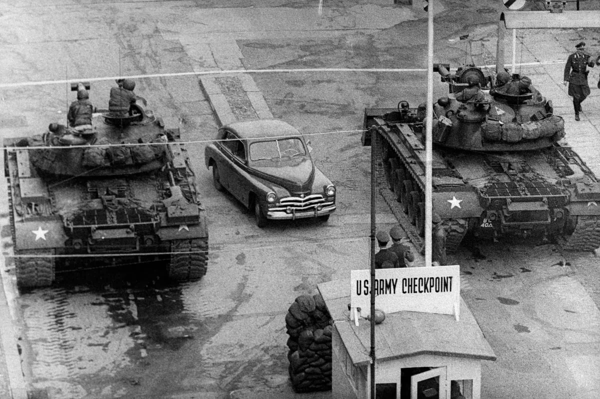 A car rides between US tanks, in October 1961, across the famous border of the American sector in Berlin, at Checkpoint Charlie crossing point, the only one in the Berlin Wall between East (Soviet sector) and West Berlin (American sector) used only by diplomats and foreigners. (AFP/Getty Images)