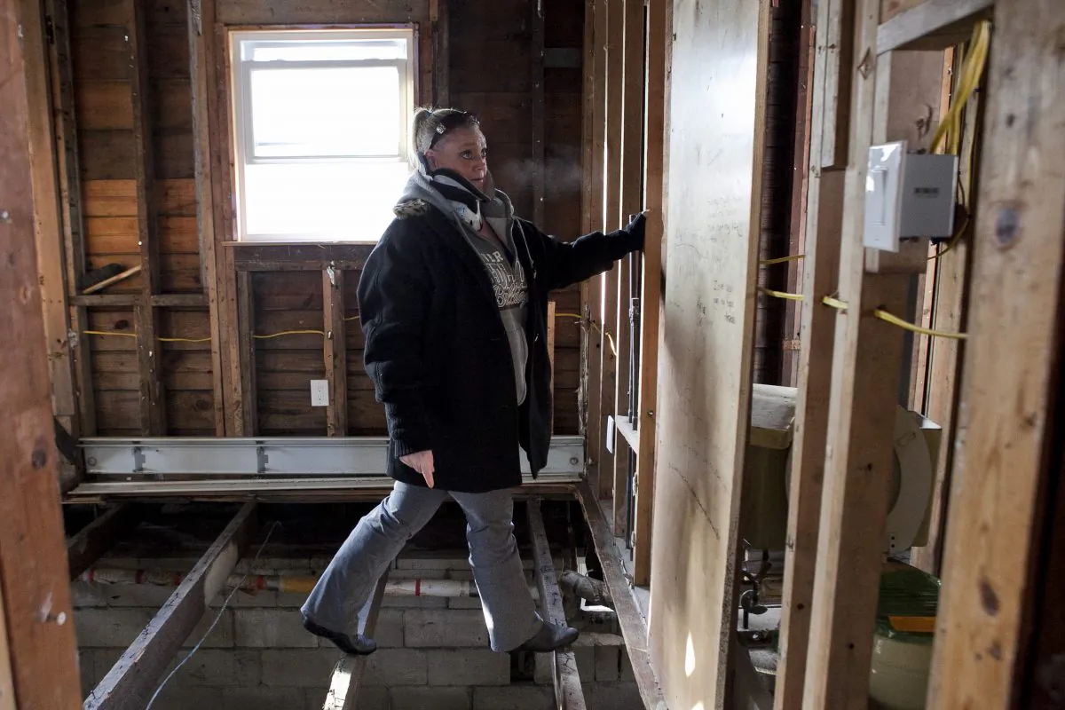 Stacey Walsh, a Build It Back applicant, navigates floor joists in her home in Broad Channel, Queens, Dec. 18, 2013. (Samira Bouaou/Epoch Times)