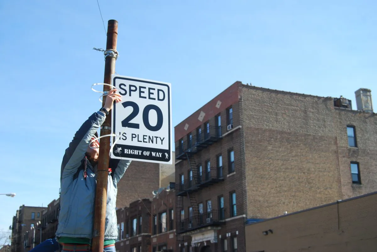 An Astoria resident puts up a "20 is Plenty" speed limit sign in Queens, New York on March 16, 2014. (Catherine Yang/Epoch Times)
