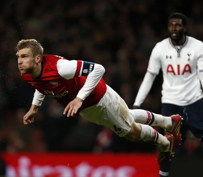Arsenal's German defender Per Mertesacker (L) launches himself at the ball during the English FA cup third round football match between Arsenal and Tottenham Hotspur at the Emirates Stadium in London on January 4, 2014. Arsenal won the game 2-0. (AFP PHOTO/ADRIAN DENNIS)