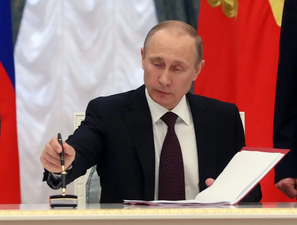 In this March 21, 2014, photo, Russian President Vladimir Putin signs bills making Crimea part of Russia in the Kremlin in Moscow. (AP Photo/Sergei Chirikov)