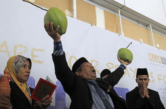 Malaysian well-known shaman Ibrahim Mat Zin, center, uses spiritual methods and prayers to locate the missing Malaysia Airlines plane MH370 at Kuala Lumpur International Airport in Sepang, Malaysia, Wednesday, March 12, 2014. The missing Malaysian jetliner may have attempted to turn back before it vanished from radar, but there is no evidence it reached the Strait of Malacca, Malaysia's air force chief said Wednesday, denying reported remarks he said otherwise. The statement suggested continued confusion over where the Boeing 777 might have ended up, more than four days after it disappeared en route to Beijing from Kuala Lumpur with 239 people on board. (AP Photo/Lai Seng Sin)