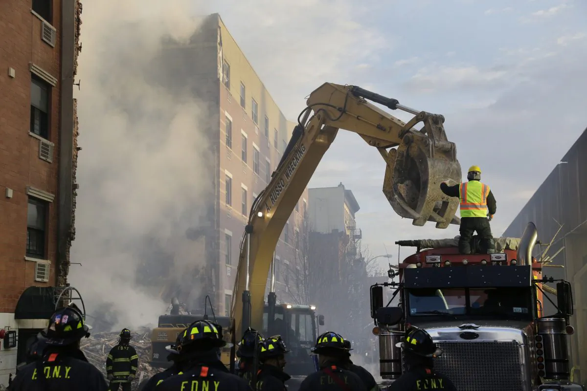 An excavator removes debris from the site of a building explosion, Thursday, March 13, 2014 in New York. Rescuers working amid gusty winds, cold temperatures and billowing smoke pulled four additional bodies Thursday from the rubble of two New York City apartment buildings, raising the death toll to at least seven from a gas leak-triggered explosion that reduced the area to a pile of smashed bricks, splinters and mangled metal. The explosion Wednesday morning in Manhattan's East Harlem injured more than 60 people. (AP Photo/Mark Lennihan)