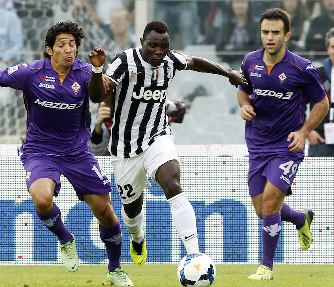 Juventus' Kwadwo Asamoah, of Ghana, center, controls the ball from Fiorentina's Mati Fernandez, of Chile, left, during a Serie A soccer match between Fiorentina and Juventus at the Artemio Franchi stadium in Florence, Italy, Sun., Oct. 20, 2013.  (AP Photo/Fabrizio Giovannozzi)