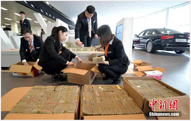 Bank tellers counting piles of money at a dealership in Hubei Province, after a customer bought in boxloads of 1 yuan notes and coins that he had been collecting for years. (Screenshot/China News) 