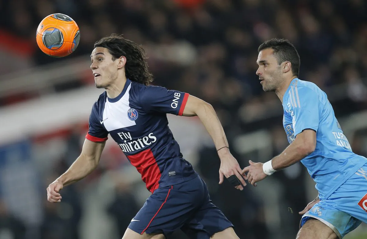 Marseille's Jeremy Morel of France, right,  challenges for the ball Paris Saint Germain's Edinson Cavani of Uruguay with during their French League One soccer match, at the Parc des Princes stadium, in Paris, Sunday, Mar. 2 , 2014. (AP Photo/Lionel Cironneau)