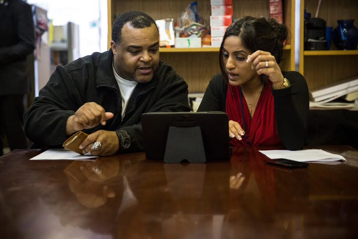 Arthur Barrett (L) works with Sherin Jose of the Bronx Community Health Network to sign up for the Affordable Care Act in the Bronx, New York, on March 31, 2014. (Andrew Burton/Getty Images)
