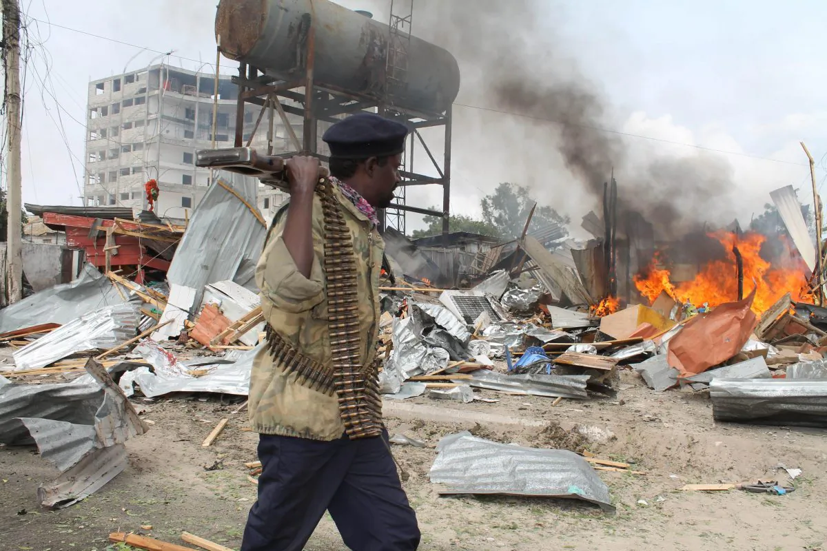 A Somali soldier walks near burning houses close to the United Nations building after a suicide bomber detonated his explosives, in Mogadishu, Somalia, July 12, 2013. (AP Photo/Farah Abdi Warsameh)