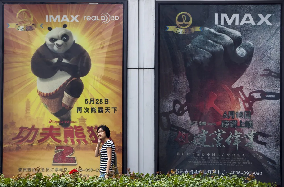A woman walks past a movie poster of "Kung Fu Panda 2" and China's propaganda film "Beginning of the Great Revival" outside a cinema in Beijing, on June 15, 2011. Dreamworks is partnering with China's state-run Shanghai Media Group to create "Kung Fu Panda 3." (Andy Wong/AP Photo)