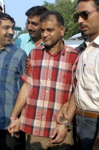 Sansar Chand, center, escorted by officials June 30, Sansar Chand, center, with offical 06/30/2005(Manan Vatsyayana/AFP/Getty Images) 