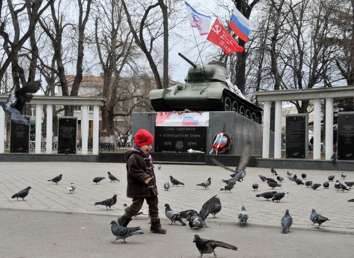 A boy with Russian flag ribbon walks in front of a monument displaying a T-34 tank in Simferopol, Crimea, on March 2, 2014. (Genya Savilov/AFP/Getty Images)