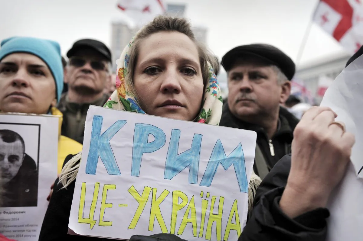 A woman holds a placard reading ‘Crimea is Ukraine’ while people attend a rally against Russia on Kyiv's Independence square March 2, 2014. (Louisa Gouliamaki/AFP/Getty Images)