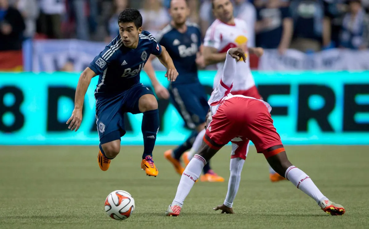 Vancouver’s Uruguayan midfielder Sebastian Fernandez evades New York’s French striker Peguy Luyindula as MLS kicked off in Vancouver, Canada on Mar. 8, 2014. (The Canadian Press/Darryl Dyck) 