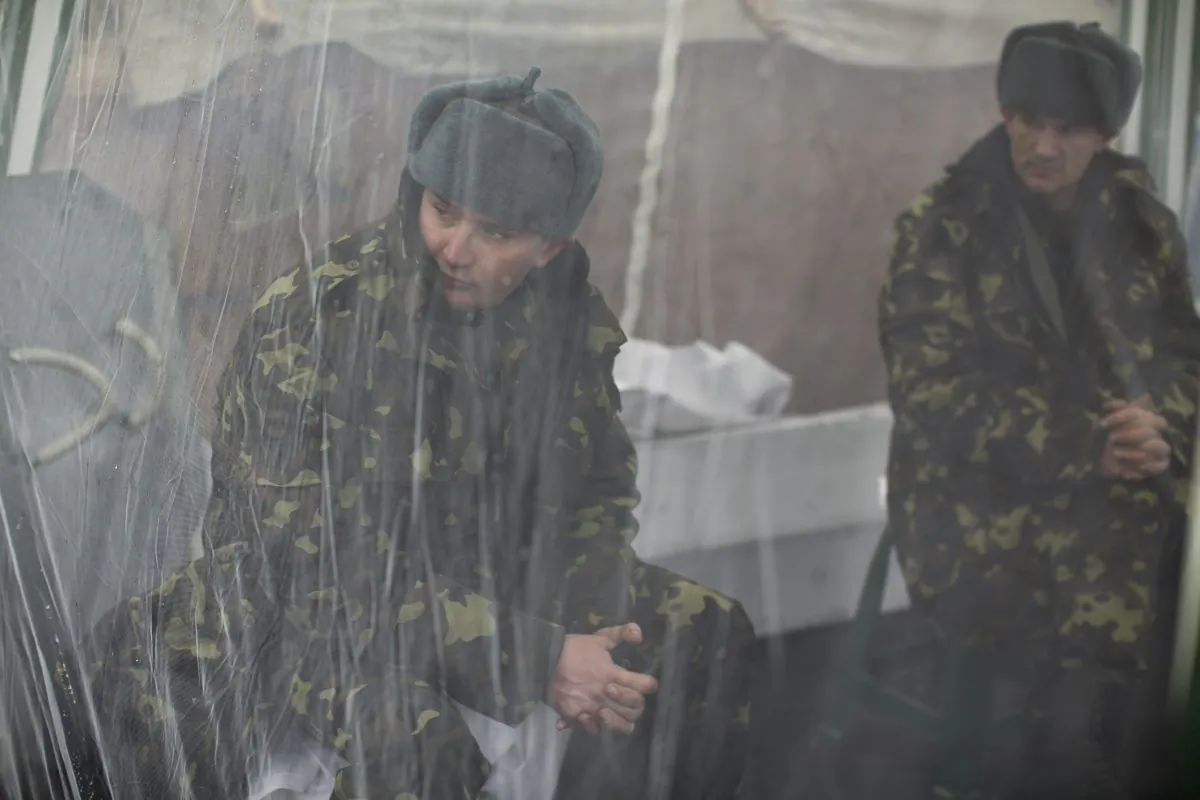 Anti-Yanukovych protesters sit inside a tent as they guard one of the entrances in Kyiv's Independence Square, the epicenter of the country's current unrest, on March 2, 2014. A convoy of hundreds of Russian troops is heading toward the regional capital, Simferopol, on the Crimean peninsula in Ukraine today. (AP Photo/Emilio Morenatti)