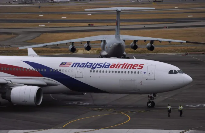 A Malaysia Airlines plane, foreground, prepares to go out onto the runway and passes by a stationary Chinese Ilyushin 76 aircraft at Perth International Airport in Perth, Australia, Tuesday, March 25, 2014. (AP Photo/Greg Wood, Pool)