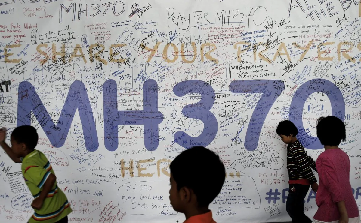 Children run past dedication messages and well wishes displayed for passengers and others involved with the missing Malaysia Airlines jetliner MH370 on the walls of the Kuala Lumpur International Airport, Thursday, March 13, 2014, in Sepang, Malaysia. (AP Photo/Wong Maye-E)