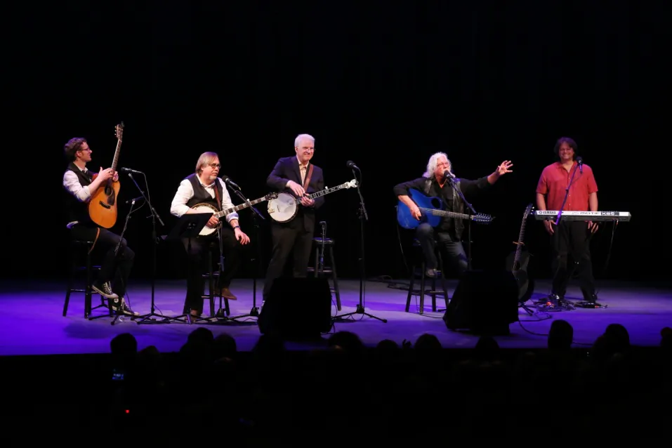 Steve Martin joins Arlo Guthrie in celebrating a Woody Guthrie Award that was posthumously awarded to Pete Seeger (Courtesy of Grammy Museum.com; WireImage.com/ Cindy Ord)