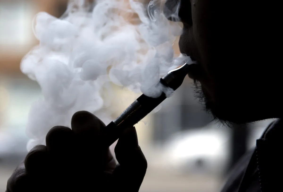 Daryl Cura demonstrates an e-cigarette at Vape store in Chicago, on April 23, 2014. The federal government wants to ban sales of electronic cigarettes to minors and require approval for new products and health warning labels under regulations being proposed by the Food and Drug Administration. (Nam Y. Huh/AP Photo)
