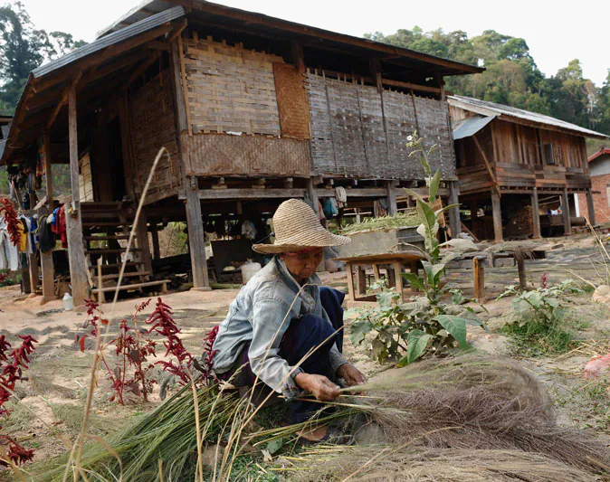 This picture taken on March 11, 2011 shows a woman working in front of her home inside Bopiat village in the Northern province of Louang Namtha where Chinese workers are carrying out drilling works for soil analyses in preparation of building a railway linking China to Laos. The people of Bopiat have particular reason to resent the Chinese workmen drilling in the centre of their village in the mountainous far north of Laos. Around a thousand of them have been told to move because their homes lie in the path of a planned high-speed railway line, funded by Beijing, that will cut across Southeast Asia's smallest economy from the Chinese border to Vientiane. (Hoang Dinh Nam/AFP/Getty Images)