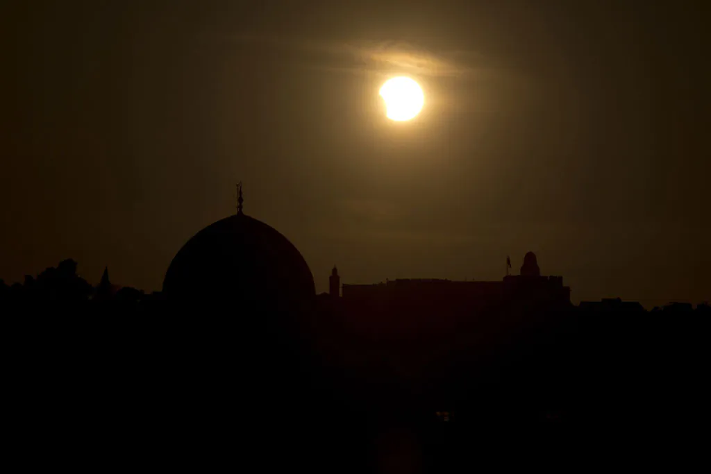 A partial eclipse is seen during sunset over the Dome of the Rock, a Muslim holy site, in Jerusalem's old city, on November 3, 2013. The rare solar eclipse will sweep across parts of Africa, Europe and the United States as the moon blocks the sun either fully or partially, depending on the location. (Menahem Kahana/AFP/Getty Images)