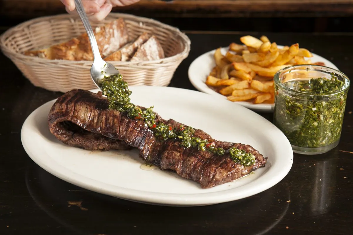 Drizzling chimichurri sauce on the skirt steak. (Samira Bouaou/Epoch Times)
