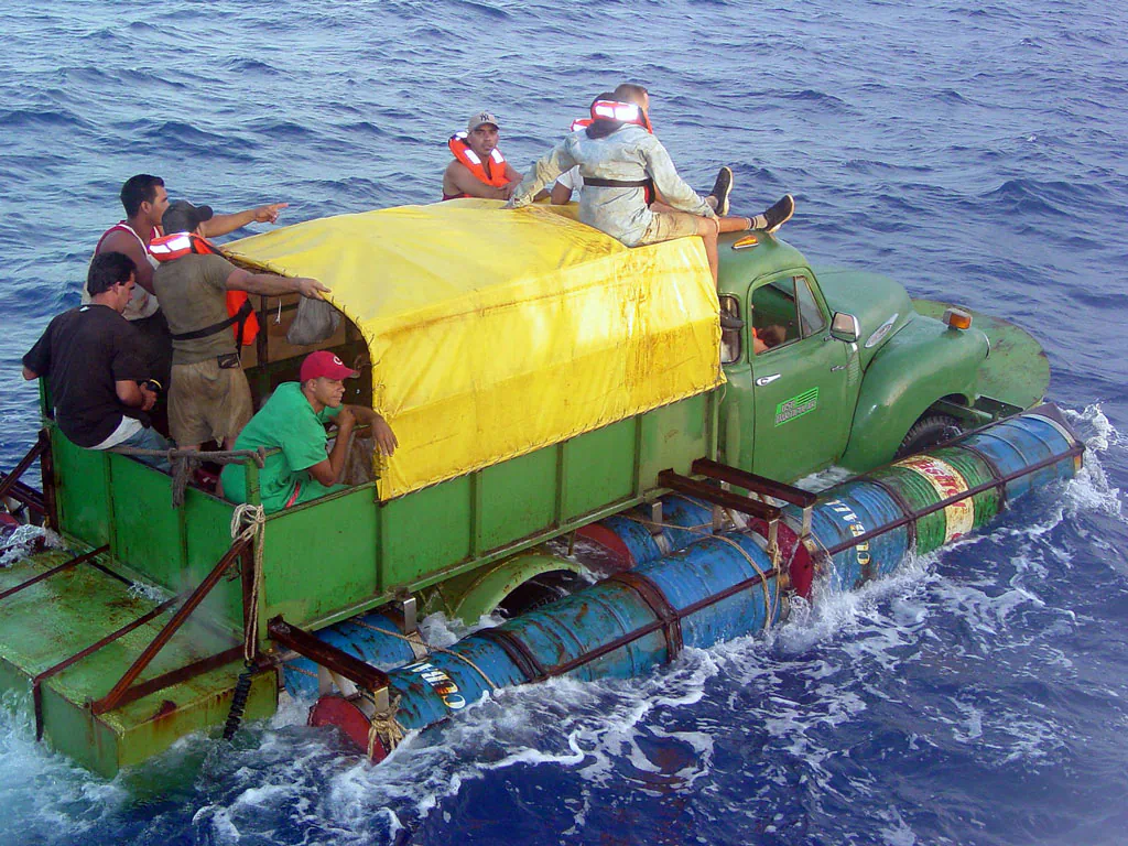 In this U.S. Coast Guard handout, Cuban migrants trying to reach the U.S. coast in Florida ride a makeshift boat made out of a 1951 Chevrolet truck with a propeller driven off the drive shaft July 16, 2003 off the coast of Florida. (Gregory Ewald/ U.S. Coast Guard/ Getty Images)