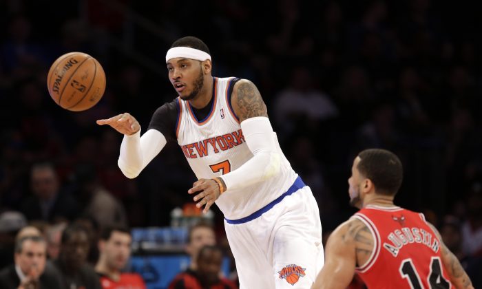 New York Knicks' Carmelo Anthony, left, passes the ball past Chicago Bulls' D.J. Augustin during the first half of the NBA basketball game, Sunday, April 13, 2014 in New York. The Knicks defeated the Bulls 100-89. (AP Photo/Seth Wenig)