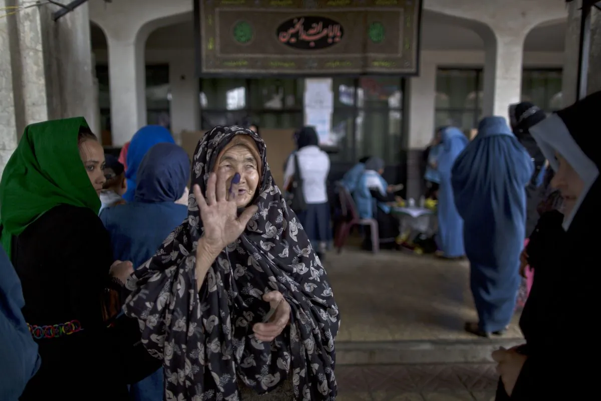 An elderly Afghan woman shows another woman her inked finger after casting her ballot at a polling station in Kabul, Afghanistan, Saturday, April 5, 2014. Afghan voters lined up for blocks at polling stations nationwide on Saturday, defying a threat of violence by the Taliban to cast ballots in what promises to be the nation's first democratic transfer of power. The vote will decide who will replace President Hamid Karzai, who is barred constitutionally from seeking a third term. (AP Photo/Muhammed Muheisen)