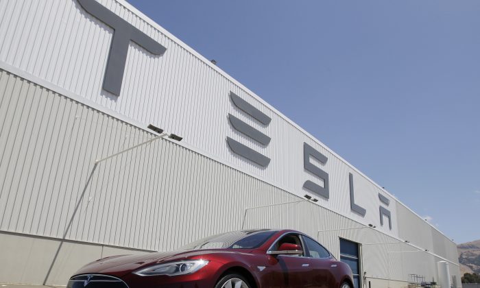 This June 22, 2012 file photo shows a Tesla Model S driving outside the Tesla factory in Fremont, Calif. (AP Photo/Paul Sakuma, File)