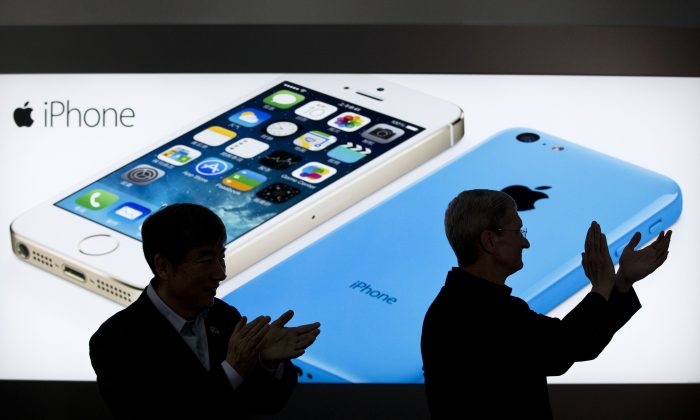 In this Jan. 17, 2014 file photo, Apple CEO Tim Cook, right, and China Mobile's chairman Xi Guohua are silhouetted against a screen showing iPhone products as they applaud during a promotional event that marks the opening day of sales of China Mobile's 4G iPhone 5s and iPhone 5c at a shop of the world's largest mobile phone operator in Beijing, China. The high-stakes battle between the world's largest smartphone makers is scheduled to wrap up this week after a monthlong trial that has pulled the curtain back on just how very cutthroat the competition is between Apple and Samsung. Closing arguments in the patent-infringement case are scheduled to begin Monday, April 28 with the two tech giants accusing each other, once again, of ripping off designs and features. At stake: $2 billion if Samsung loses, a few hundred million if Apple loses. (AP Photo/Alexander F. Yuan, File)